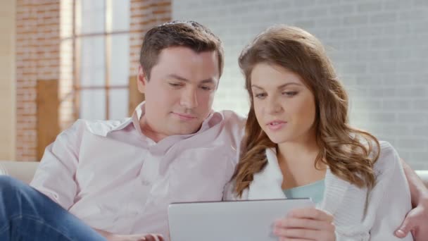 Casal conversando, ver fotos no tablet, rindo na sala de estar — Vídeo de Stock
