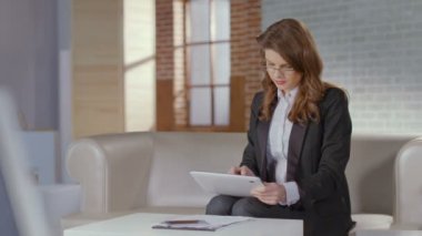 Kamera için gülümseyen tablet üzerinde çalışan kadın finansal analist