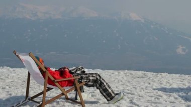 Snowboarder dağın tepesinde gadget ile sandalyede dinlenme sahip