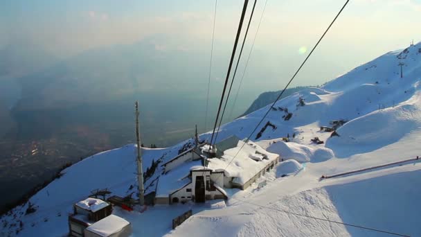 View from cableway cabin lifting skiers to snowy mountain pick — Stock Video
