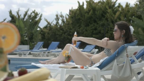 Hübsches Model, das Sonnencreme auf die Haut aufträgt, sich um den Körper kümmert — Stockvideo