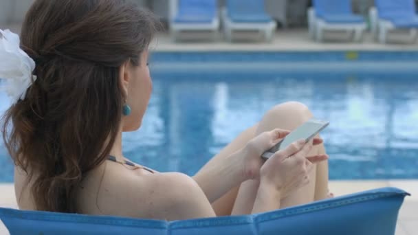 Jovem mulher número de discagem, chamando, falando ao telefone perto da piscina — Vídeo de Stock