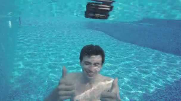 Homem feliz mostrando os polegares debaixo d 'água, nadando na piscina — Vídeo de Stock