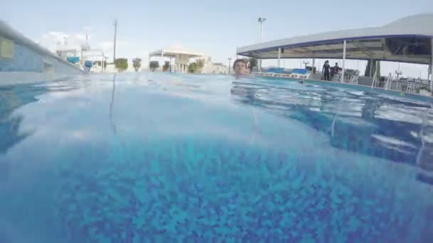 Jovem homem animado nadando na piscina, relaxante, se divertindo — Vídeo de Stock