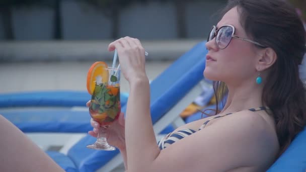 Горячая цыпочка пьет свежий коктейль на пляже, дразнит языком — стоковое видео