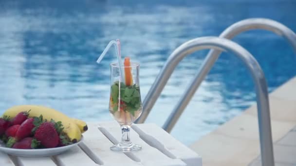 Освежающий летний коктейль, фрукты возле бассейна, стеллаж фокус — стоковое видео