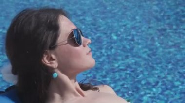 Güneş gözlüklü çekici genç kız havuz başında dinleniyor.
