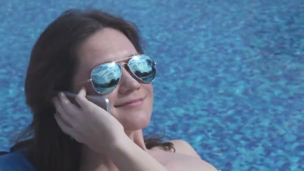Menina bonita falando no telefone perto da piscina, flertando, sorriso no rosto — Vídeo de Stock