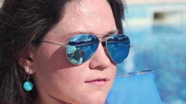 Pretty kadın vücuda güneş kremi yağı koyar, güneş gözlüğü yansıması