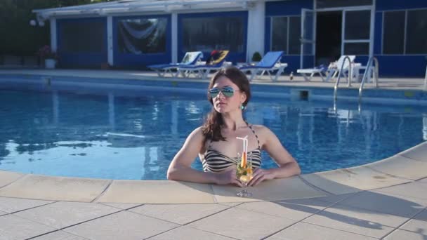 Hete alleenstaande vrouw in bikini genieten van een cocktail in het zwembad — Stockvideo