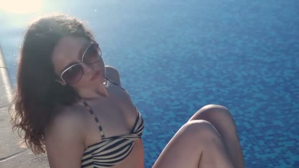 Upset lonely woman sitting by swimming pool, sunny summer beach — Stock Video