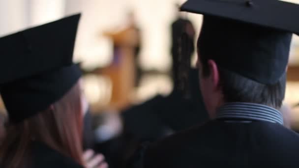 Jeunes gens heureux dans des casquettes académiques avec glands parler à la cérémonie de remise des diplômes — Video