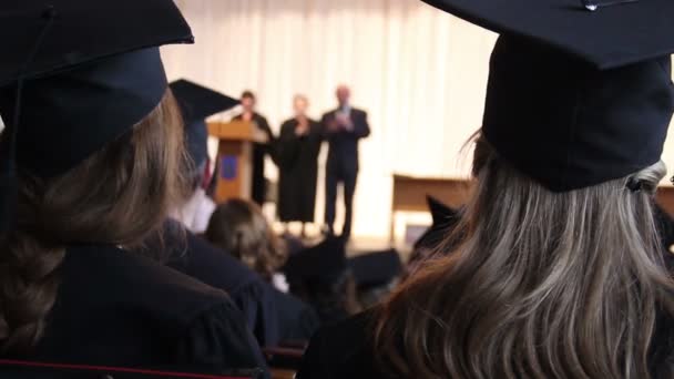 Många unga killar lyssnar på rektorns tal vid college examensceremoni — Stockvideo