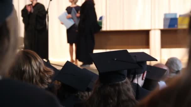Выпускники программы MBA получают дипломы на сцене, пожимая руку профессору — стоковое видео