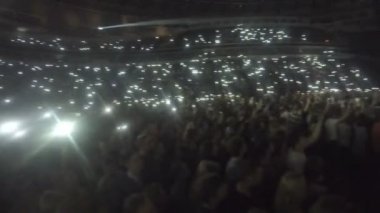Kalabalık telefonları karanlıkta sallayarak fanlar. Popüler slow şarkı sırasında ışıklar ışıltı