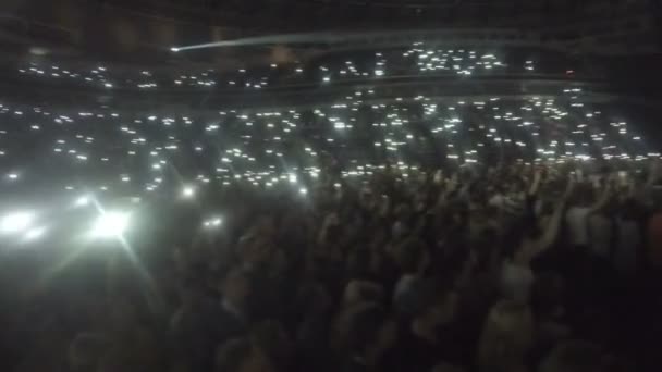 Натовп шанувальників махав телефонами в темряві. Світло іскриться під час популярної повільної пісні — стокове відео