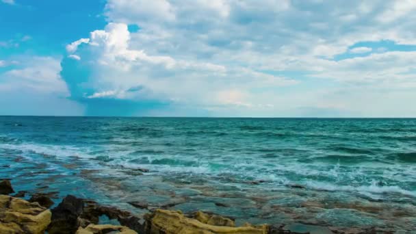 Las olas del mar salpicando en la playa pedregosa, nubes bajas en el cielo. Video Loopable con sonido — Vídeo de stock