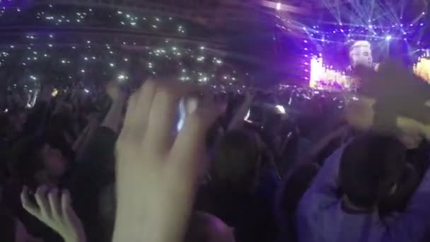 ミンスク、ベラルーシ - 2015年4月15日。ロビー・ウィリアムズがミンスク・アリーナでコンサートを行いました。ロビー・ウィリアムズのコンサートで歌いながら、興奮したファンが手を振る。きらめくライト — ストック動画