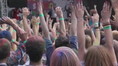 Sahneden kalabalığa boya tozu atan adam, festivalin tadını çıkaran insanlar, eller yukarı