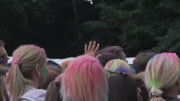 Menge junger Menschen mit Farbe beschmiert, die bei Fest buntes Pulver in die Luft werfen — Stockvideo