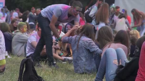 Kiev, Oekraïne-11 juni 2015. Viering van Holi kleur Festival. Gelukkige jonge mensen op open air festival zittend op het gras met snacks, chatten — Stockvideo