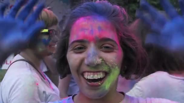 Kiev, Ukrayna-11 Haziran 2015. Holi renkli Festivali kutlamaları. Güzel kız closeup söz, kameraya, mutlu kalabalık göz kırpıyor boya kaplı — Stok video