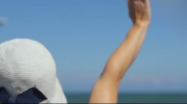 İniş uçağına bakan kadın, yeni gelen turistleri karşılamak için el sallıyor.