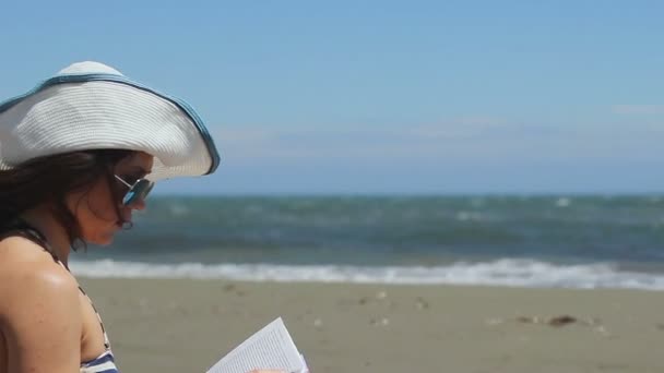 Junge Frau liest Buch am Strand, Flugzeug fliegt über Küste, Touristen kommen an — Stockvideo