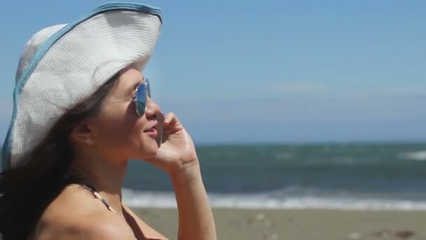 Возбужденная молодая женщина на пляже эмоционально разговаривает по телефону, машет руками, улыбается — стоковое видео