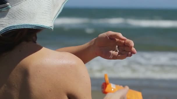 Femme utilisant des produits cosmétiques écran solaire pour les soins de santé, bains de soleil sur une plage de sable ensoleillée — Video