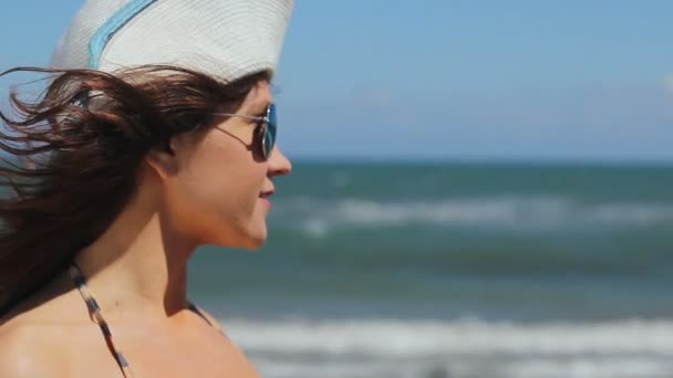 Крупный план молодой женщины в солнечных очках, наслаждающейся отдыхом на солнечном пляже на берегу моря — стоковое видео