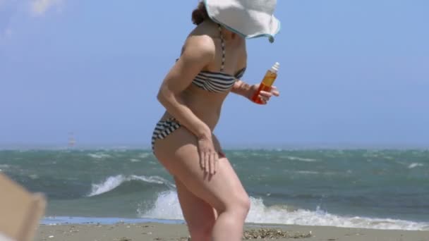 Femmina calda sfregamento fianchi, applicazione di spray solare, abbronzatura sulla spiaggia estiva — Video Stock