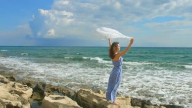 ağır çekim beyaz uzun elbise sallayarak içinde güzel Bayan eşarp kayalık plaj