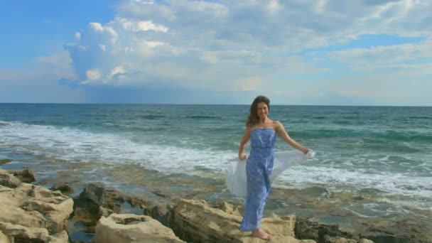 Felice bella donna in piedi sulla spiaggia rocciosa del mare, onde schiumose schiantarsi a terra — Video Stock