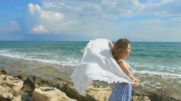 Mujer atractiva joven sosteniendo bufanda blanca en el viento en la orilla del mar, la libertad — Vídeos de Stock