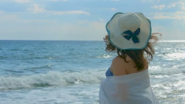 Femme enveloppée dans une écharpe blanche regardant les belles vagues de l'océan, au début de l'automne — Video