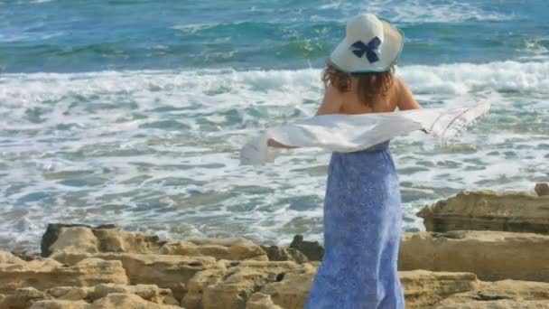 Slow-motion of attractive woman in long dress watching sea waves on rocky shore — Stock Video
