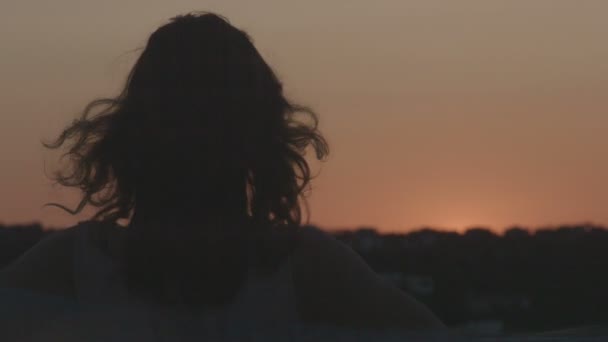 Silueta femenina disfrutando de la vista del cielo rosa al atardecer, sosteniendo la bufanda en el viento — Vídeos de Stock