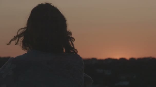 Eenzame vrouw kijken naar sky branden bij zonsopgang, zonsondergang. Haren waait in de wind — Stockvideo