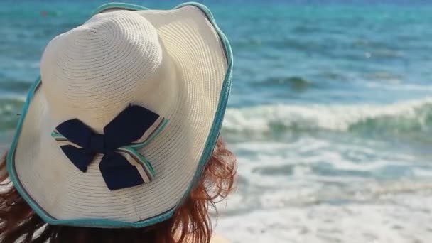 Close-up de morena fêmea de chapéu olhando para as ondas do mar, desfrutando de férias de verão — Vídeo de Stock