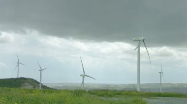 Kötü hava yağmurlu gri fırtınalı gökyüzü altındaki yeşil alanında iplik Rüzgar türbinleri
