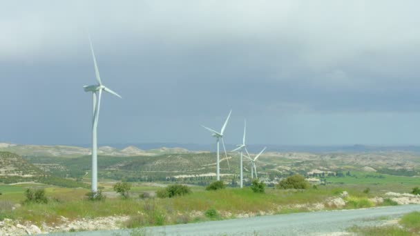 Fonte di energia rinnovabile, moderni mulini a vento filatura, campo verde, orizzonte tempestoso — Video Stock