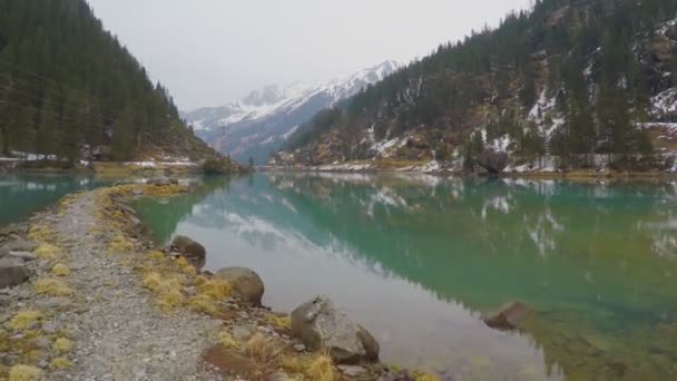 Stony lakeside, forest and mountains reflection in water, electric power lines — Stock Video