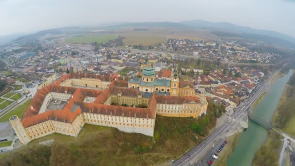 Aerial shot of beautiful Baroque abbey standing atop town Melk and river Danube — Stock Video