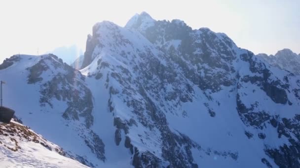 Senkrecht aufragende schneebedeckte Berge und strahlende Sonne am blauen Himmel. Winterlandschaft — Stockvideo