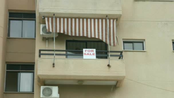 Продается табличка на балконе квартиры. Услуги агентства недвижимости. Долговой кризис — стоковое видео