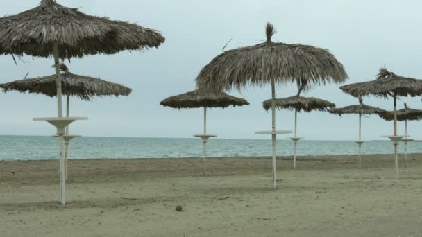 Ombrelloni sulla spiaggia vuota. Onde che schizzano nel mare tempestoso. Fuori stagione al resort — Video Stock