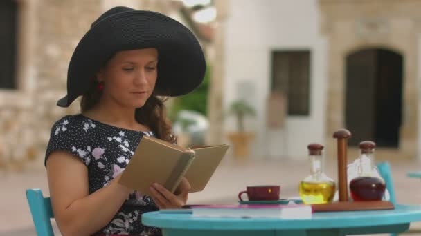 Vacker kvinna läser gamla papper bok i café, njuter av vila, avkoppling på semester — Stockvideo