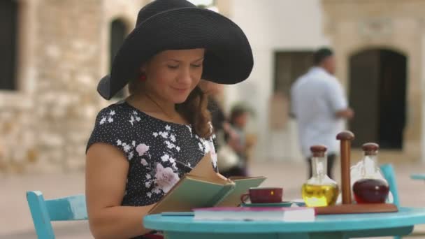Unga kvinnliga författare att göra anteckningar i anteckningsboken, njuter resten i utomhus café — Stockvideo