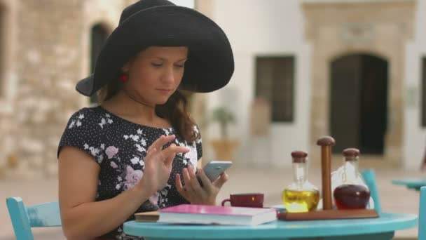 Bella ragazza seduta in strada caffè, digitando il messaggio, chiacchierando su smartphone — Video Stock